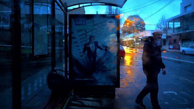 A man waits at a shelter for a bus in Leichhardt this morning. Photo: Kate Geraghty