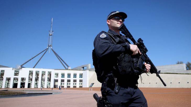 An AFP officer armed with a machine gun patrols outside the front of Parliament House. Photo: Andrew Meares