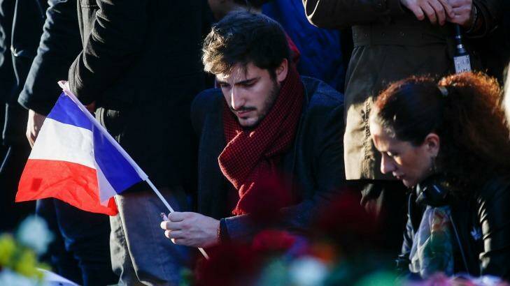 A mourner holds a French national flag as he pays his respects to victims of the terrorist attacks, at Place de la Republique. Photo: Simon Dawson