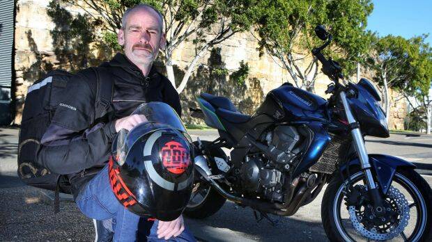 Chris Goodwin with his motorcycle which he uses to deliver Uber Eats around Sydney.  Photo: James Alcock
